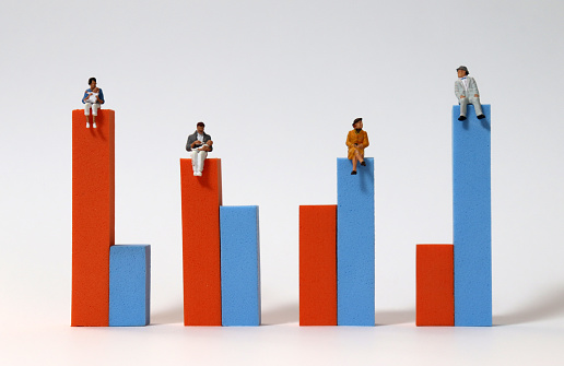 Miniature people sitting on a bar graph.